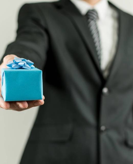 A man in a suit holding a blue small present box